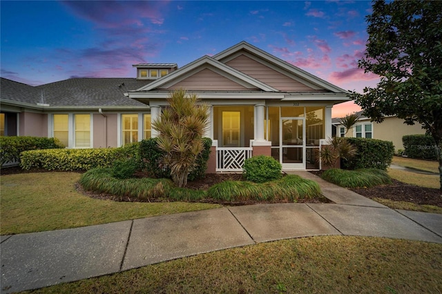 view of front of home with a lawn and a sunroom