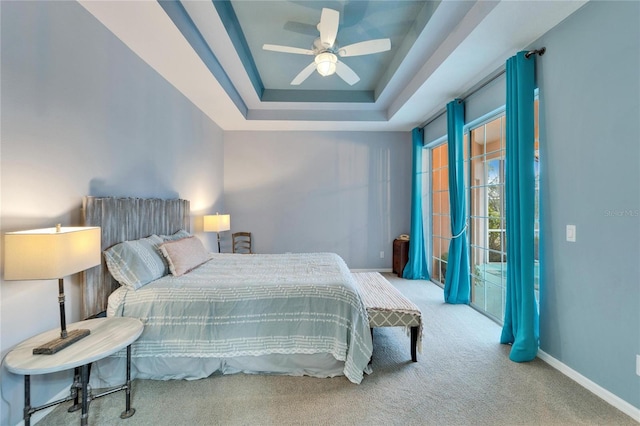 carpeted bedroom featuring ceiling fan and a tray ceiling