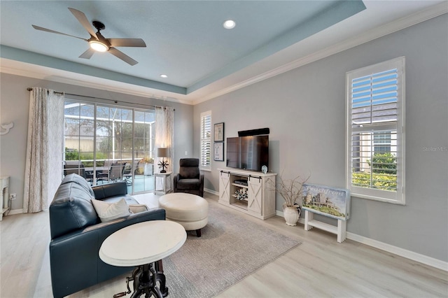 living room featuring ceiling fan, wood-type flooring, and a tray ceiling