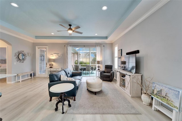 living room featuring ceiling fan, light hardwood / wood-style floors, and a tray ceiling