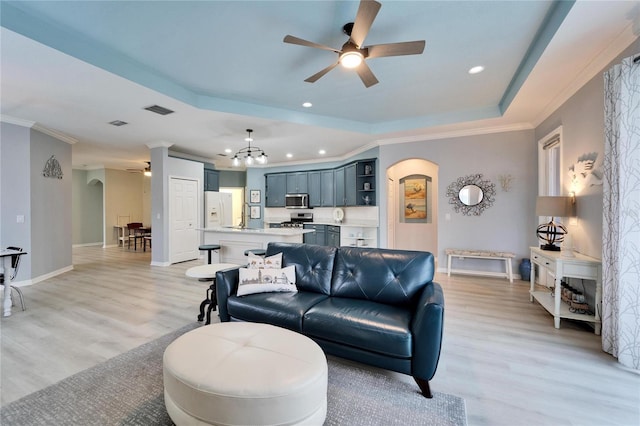 living room featuring light hardwood / wood-style floors, a tray ceiling, and ceiling fan