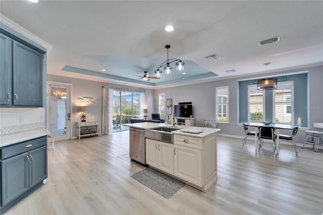 kitchen featuring light wood-type flooring, pendant lighting, dishwasher, and a tray ceiling