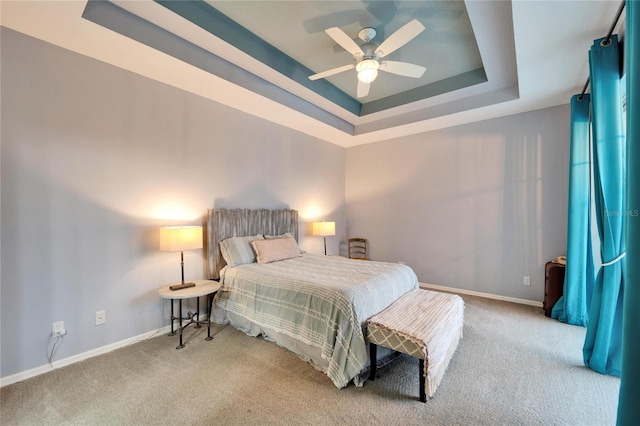 bedroom with ceiling fan, light colored carpet, and a tray ceiling