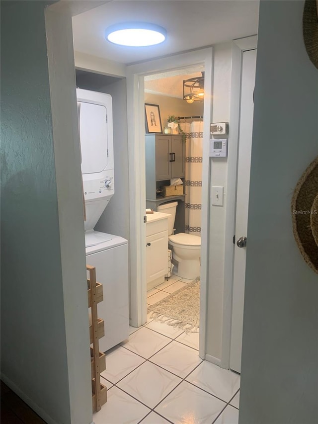 bathroom with toilet, vanity, stacked washing maching and dryer, and tile patterned flooring