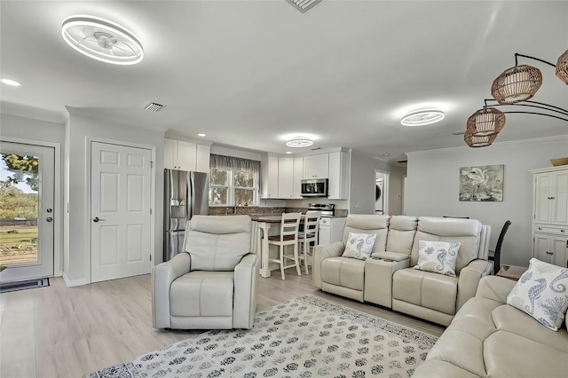 living room with light wood-type flooring and crown molding