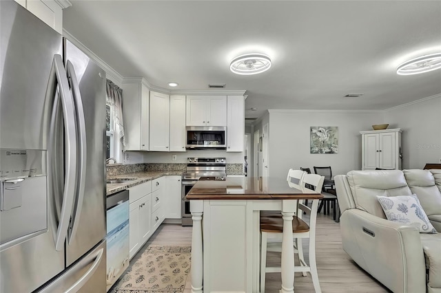 kitchen with sink, white cabinets, appliances with stainless steel finishes, and a breakfast bar