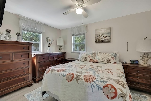 bedroom featuring ceiling fan, light hardwood / wood-style flooring, and multiple windows