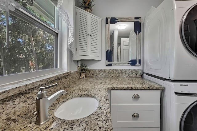 laundry area with sink and stacked washer / drying machine