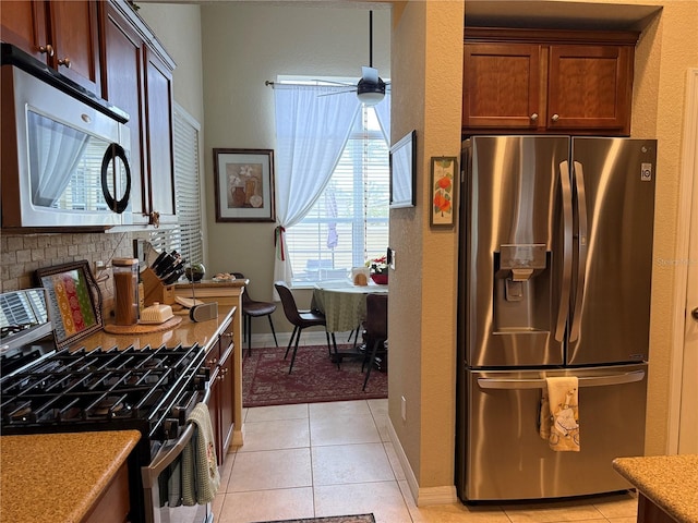 kitchen featuring light tile patterned floors, decorative backsplash, stainless steel appliances, and ceiling fan