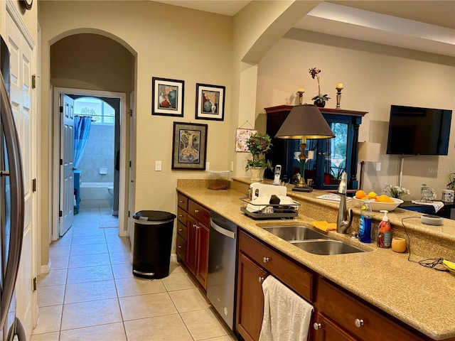 kitchen featuring dishwasher, sink, black refrigerator, and light tile patterned floors