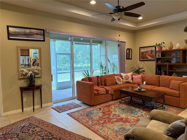 tiled living room featuring ceiling fan and a tray ceiling