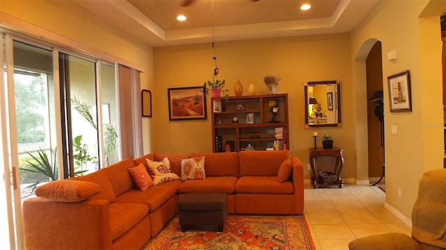 living area with arched walkways, a raised ceiling, recessed lighting, and light tile patterned floors