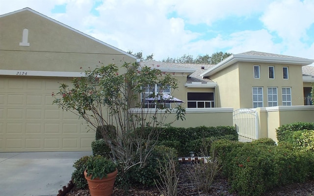 view of side of property with a garage, driveway, and stucco siding