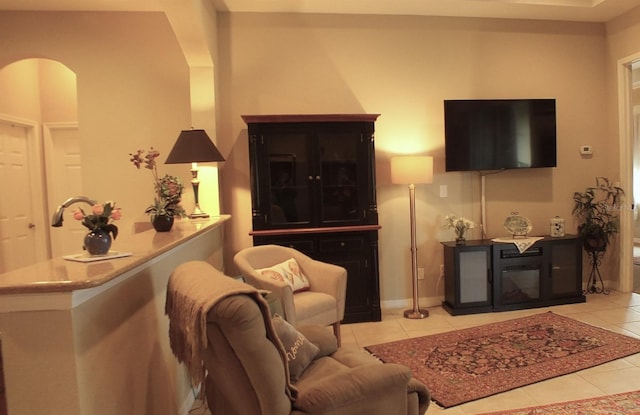 living area with light tile patterned floors, baseboards, and arched walkways