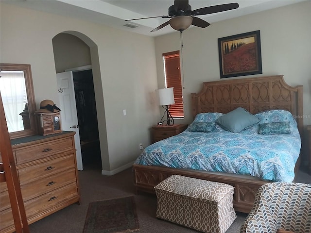 carpeted bedroom featuring arched walkways, ceiling fan, visible vents, and baseboards