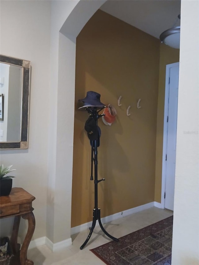 hallway featuring arched walkways and baseboards