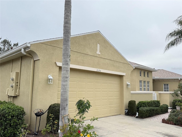 view of property exterior with an attached garage, concrete driveway, and stucco siding