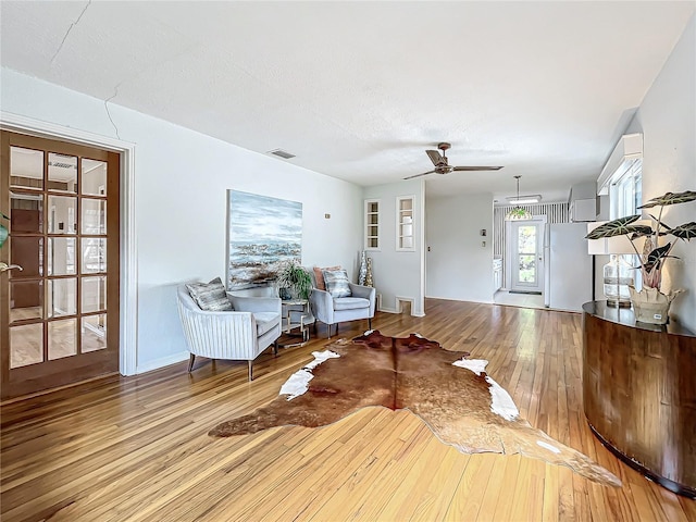 unfurnished living room with ceiling fan, built in features, a textured ceiling, and light wood-type flooring