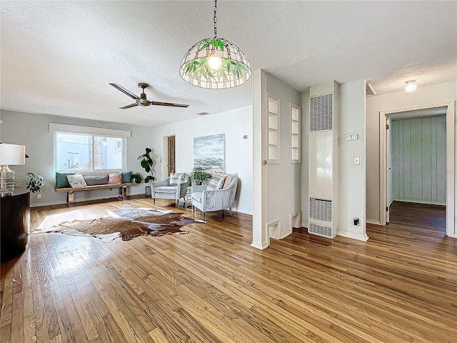 living room featuring ceiling fan, hardwood / wood-style floors, built in features, and a textured ceiling