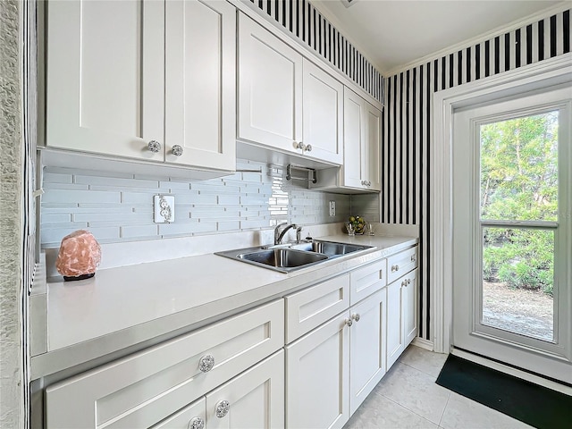 kitchen with tasteful backsplash, white cabinetry, sink, and light tile patterned floors