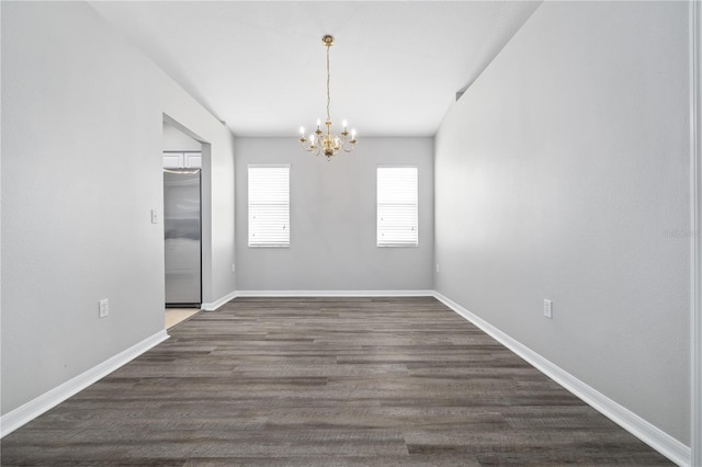 empty room with dark hardwood / wood-style flooring and an inviting chandelier