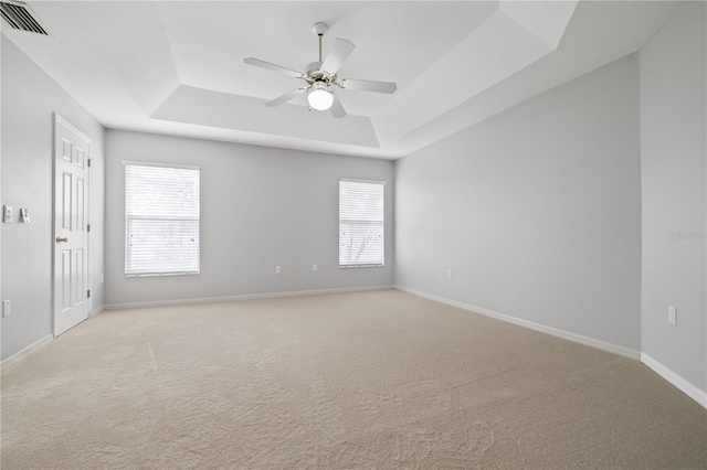 carpeted empty room with ceiling fan and a raised ceiling