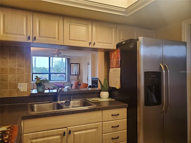 kitchen with a ceiling fan, dark countertops, stainless steel fridge, and a sink