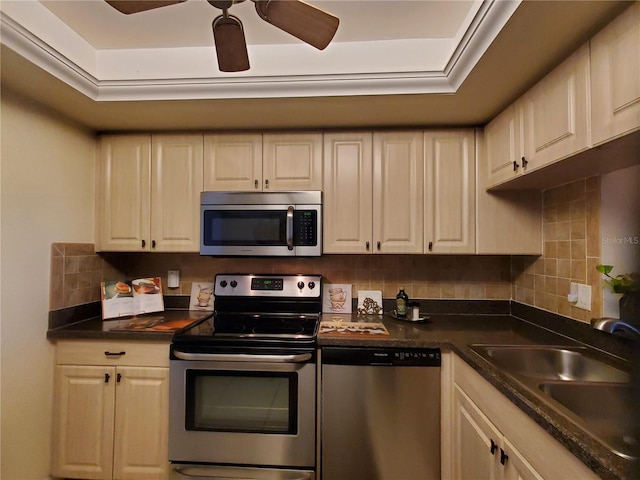 kitchen featuring stainless steel appliances, dark countertops, tasteful backsplash, a sink, and ceiling fan