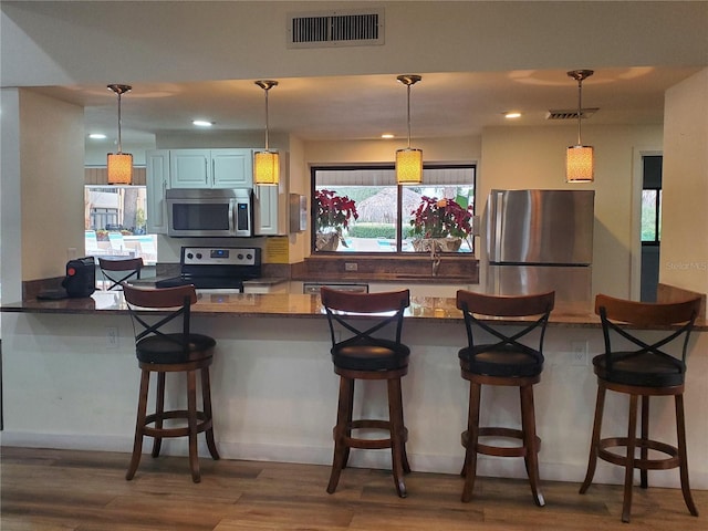 kitchen featuring stainless steel appliances, a breakfast bar area, dark countertops, and pendant lighting