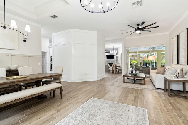 living room featuring ornamental molding and ceiling fan with notable chandelier