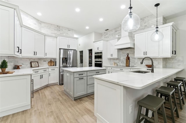 kitchen with white cabinetry, sink, a kitchen breakfast bar, and decorative light fixtures