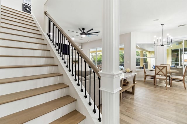 stairway with hardwood / wood-style flooring and ceiling fan with notable chandelier