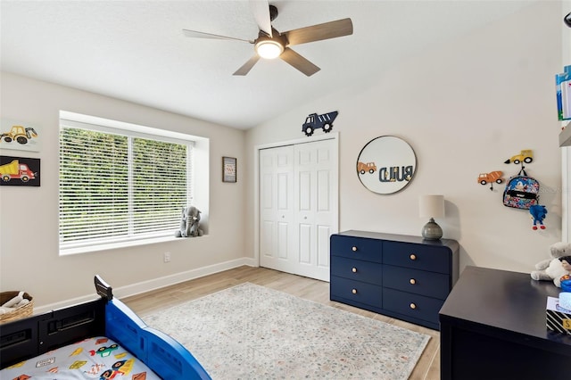 bedroom with lofted ceiling, light hardwood / wood-style flooring, ceiling fan, and a closet