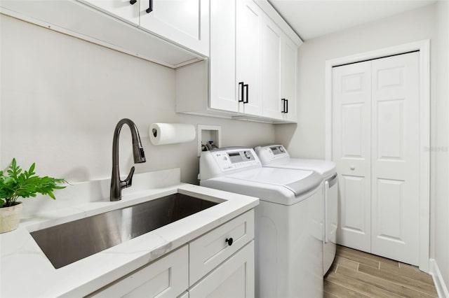 washroom with cabinets, separate washer and dryer, sink, and light hardwood / wood-style flooring