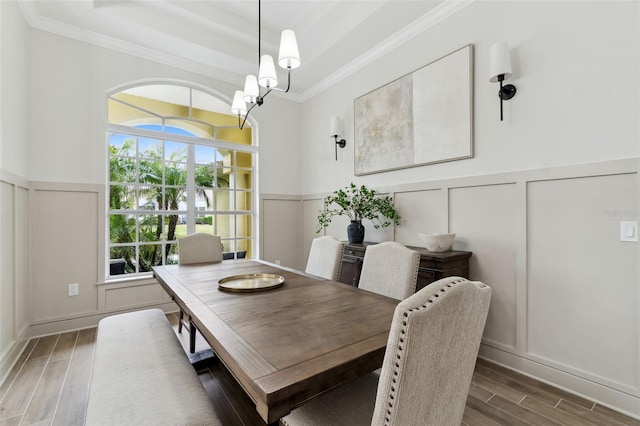 dining area with a raised ceiling, ornamental molding, and a notable chandelier