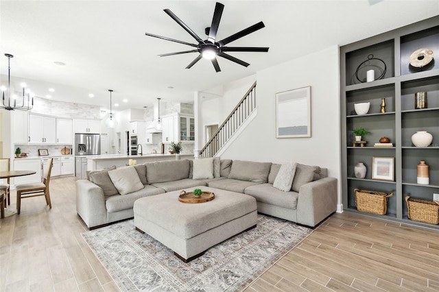 living room featuring sink, ceiling fan with notable chandelier, and light wood-type flooring