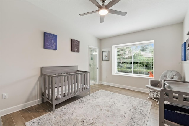 bedroom with a crib, hardwood / wood-style floors, and ceiling fan