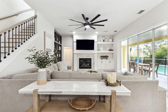 living room with built in shelves, ceiling fan, and a fireplace