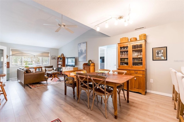 dining area featuring ceiling fan, lofted ceiling, rail lighting, and light hardwood / wood-style flooring