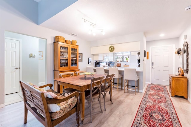 dining area with track lighting and light hardwood / wood-style flooring