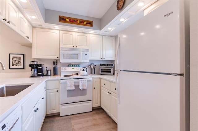 kitchen with sink, white appliances, white cabinets, and light wood-type flooring