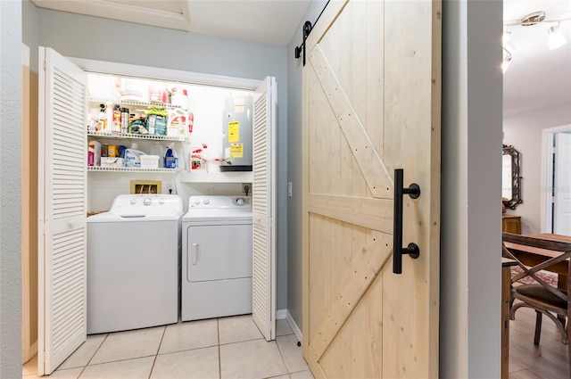 laundry area featuring water heater, independent washer and dryer, light tile patterned floors, and a barn door