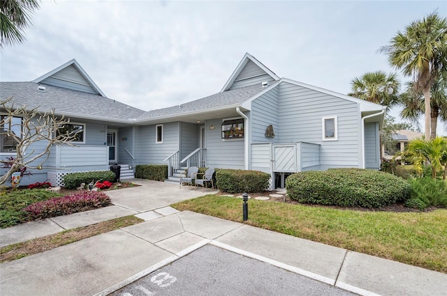 1018 Caravel Ct, Tarpon Springs, FL 34689 - view of front of property with entry steps, a shingled roof, and a front lawn