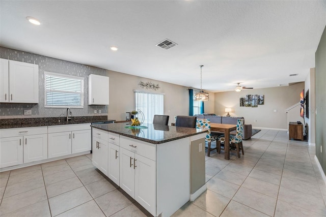 kitchen with a center island, dark stone countertops, white cabinetry, and hanging light fixtures