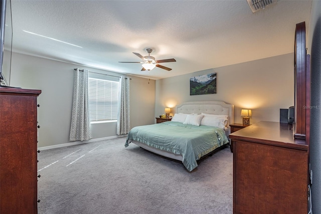 carpeted bedroom featuring ceiling fan and a textured ceiling