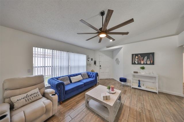 living room featuring vaulted ceiling, ceiling fan, and a textured ceiling