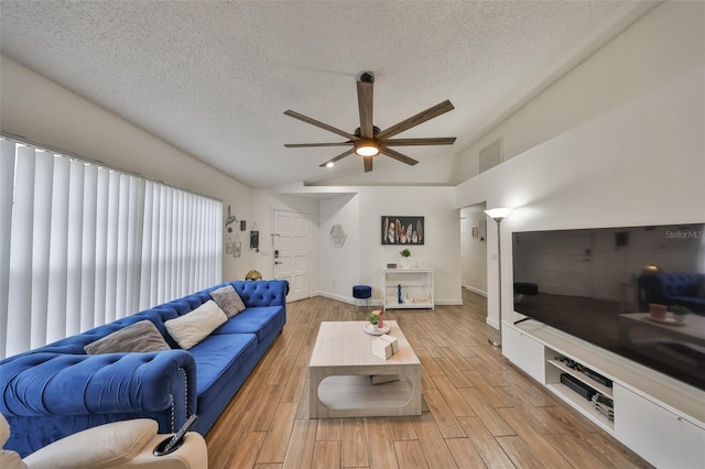 living room featuring ceiling fan, vaulted ceiling, and a textured ceiling