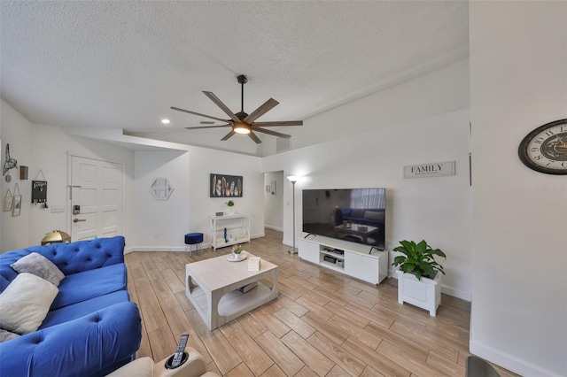 living room featuring ceiling fan, a textured ceiling, and vaulted ceiling