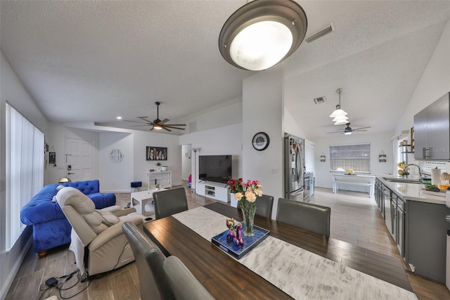 dining area with vaulted ceiling, ceiling fan, a textured ceiling, and sink