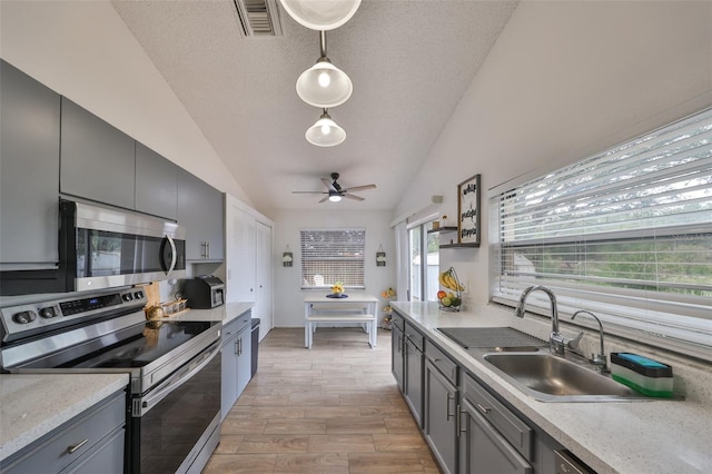 kitchen featuring a textured ceiling, appliances with stainless steel finishes, lofted ceiling, and hanging light fixtures